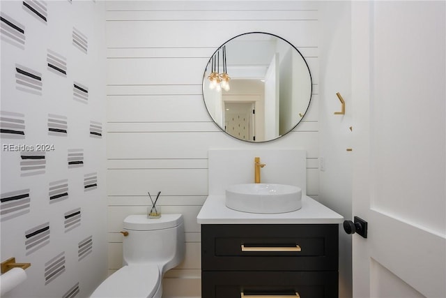 bathroom with vanity, wooden walls, and toilet