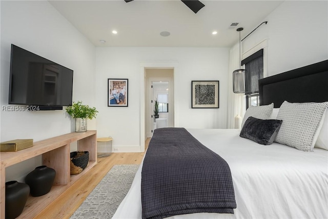 bedroom with connected bathroom and light hardwood / wood-style flooring