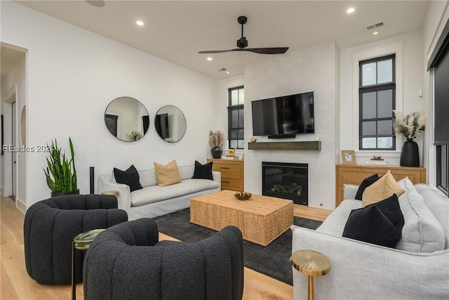 living room with a fireplace, light hardwood / wood-style flooring, and ceiling fan