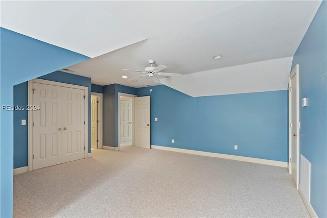 unfurnished bedroom featuring ceiling fan, vaulted ceiling, and light carpet