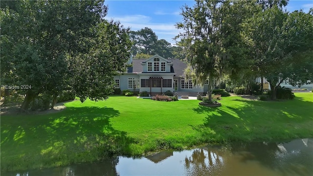 back of property featuring a water view and a yard