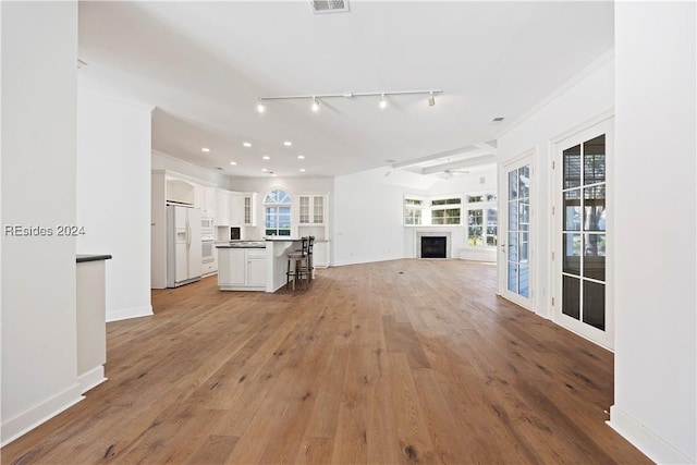 unfurnished living room with crown molding, light hardwood / wood-style flooring, ceiling fan, and track lighting