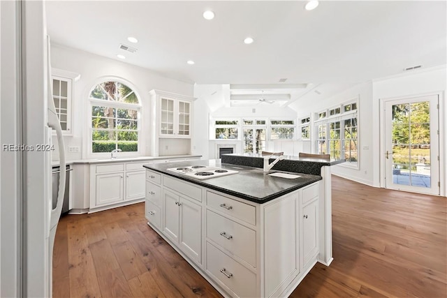 kitchen with white electric stovetop, a center island, hardwood / wood-style floors, and white cabinets