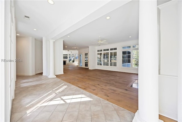 unfurnished living room with light tile patterned flooring, ceiling fan, and ornate columns