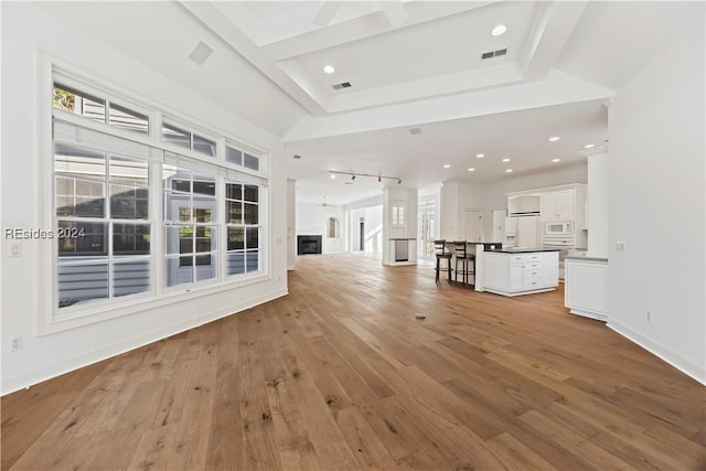 unfurnished living room featuring rail lighting and light hardwood / wood-style flooring