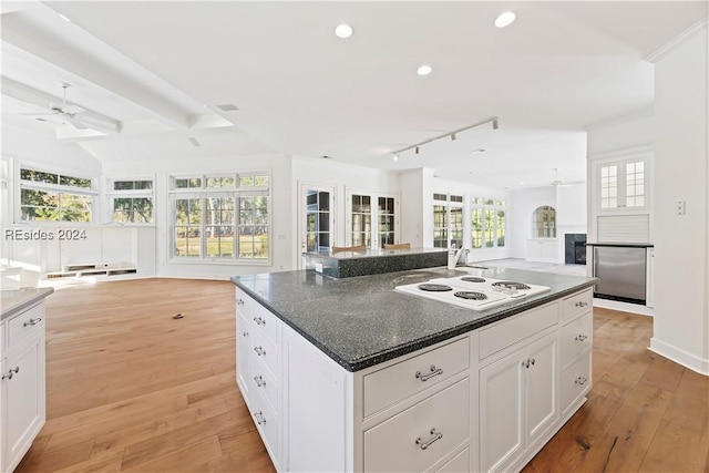 kitchen with white electric stovetop, white cabinetry, a center island, beamed ceiling, and light wood-type flooring