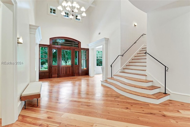 foyer featuring an inviting chandelier, a towering ceiling, and hardwood / wood-style floors