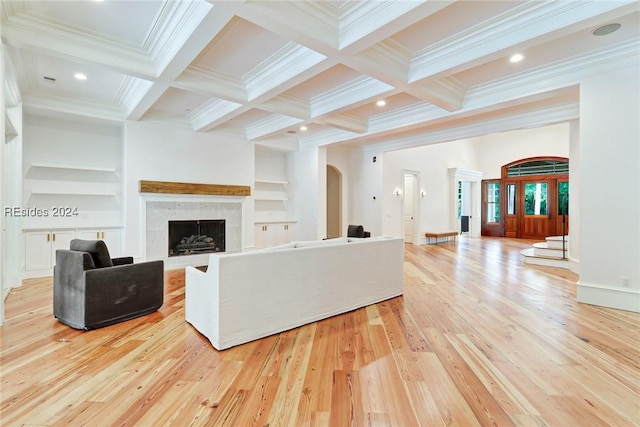 living room featuring a premium fireplace, coffered ceiling, built in shelves, beamed ceiling, and light wood-type flooring