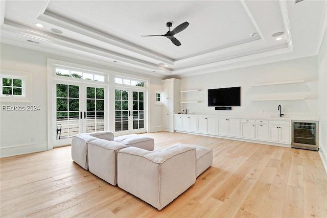 living room with wine cooler, a raised ceiling, and light hardwood / wood-style flooring