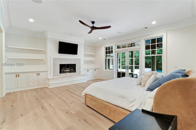 bedroom with a fireplace, light hardwood / wood-style flooring, ornamental molding, ceiling fan, and french doors