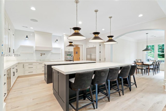 kitchen featuring pendant lighting, tasteful backsplash, white cabinetry, a kitchen breakfast bar, and a large island