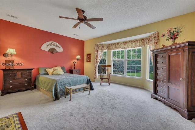 bedroom with a textured ceiling, light colored carpet, and ceiling fan