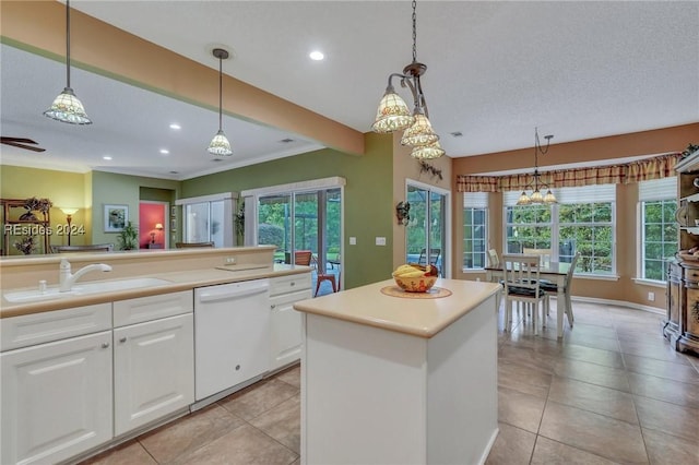 kitchen with pendant lighting, sink, dishwasher, white cabinetry, and a center island