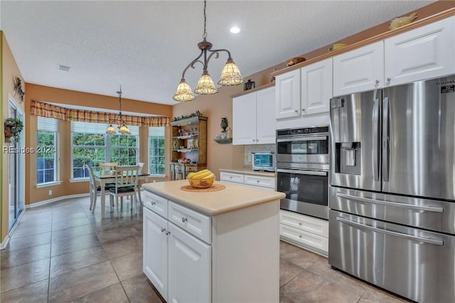 kitchen with decorative light fixtures, a textured ceiling, white cabinets, and appliances with stainless steel finishes