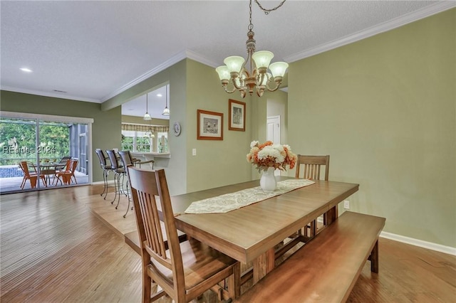 dining area featuring an inviting chandelier, ornamental molding, wood-type flooring, and a textured ceiling