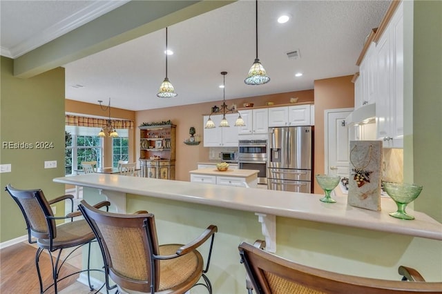 kitchen with white cabinetry, appliances with stainless steel finishes, kitchen peninsula, pendant lighting, and backsplash