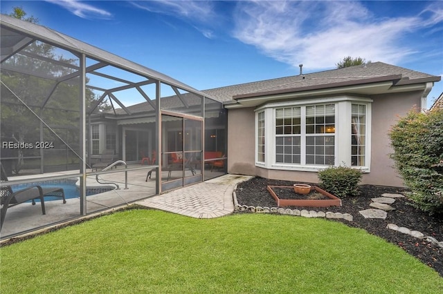 rear view of house with a yard, a patio area, and glass enclosure