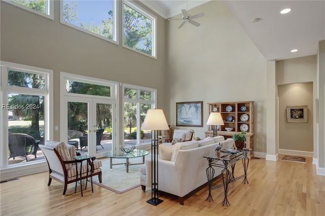 living room featuring french doors, a towering ceiling, ceiling fan, and light hardwood / wood-style floors