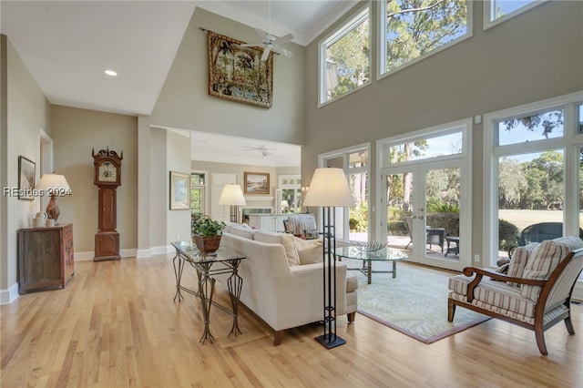 living room with a towering ceiling, plenty of natural light, light hardwood / wood-style floors, and ceiling fan