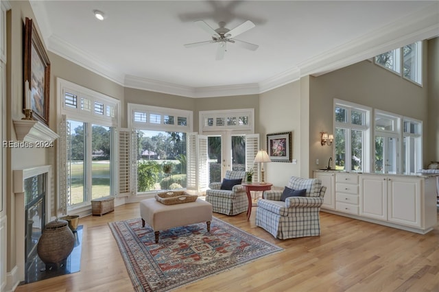 interior space with ceiling fan, ornamental molding, a fireplace, and light hardwood / wood-style flooring