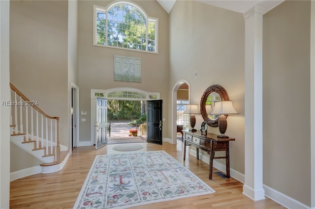 foyer entrance with a towering ceiling and light wood-type flooring