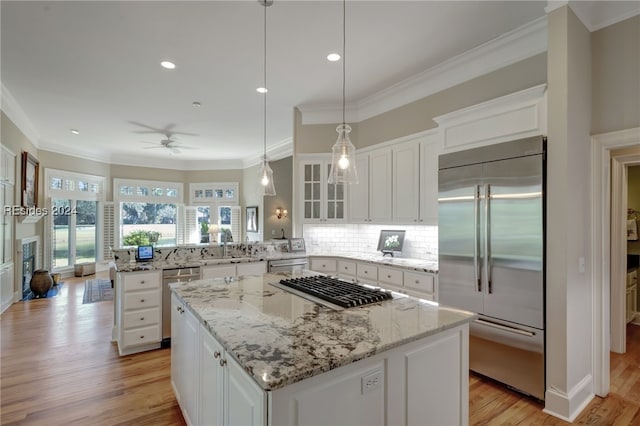 kitchen featuring stainless steel appliances, kitchen peninsula, white cabinets, and a center island