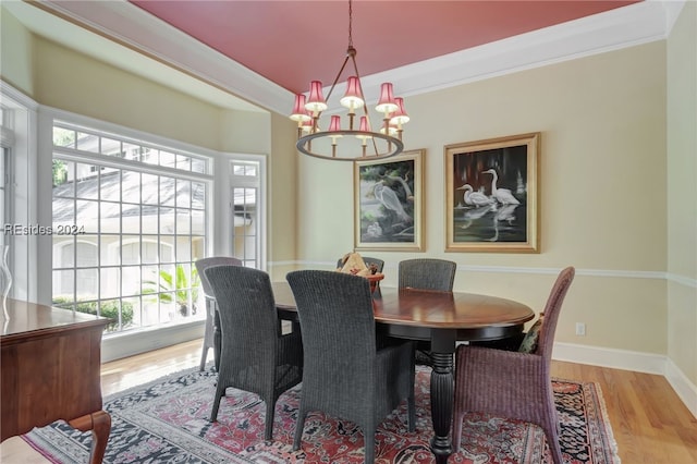 dining space with crown molding, an inviting chandelier, and light hardwood / wood-style floors