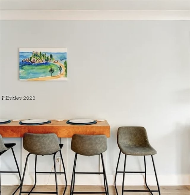 dining space with ornamental molding and light wood-type flooring