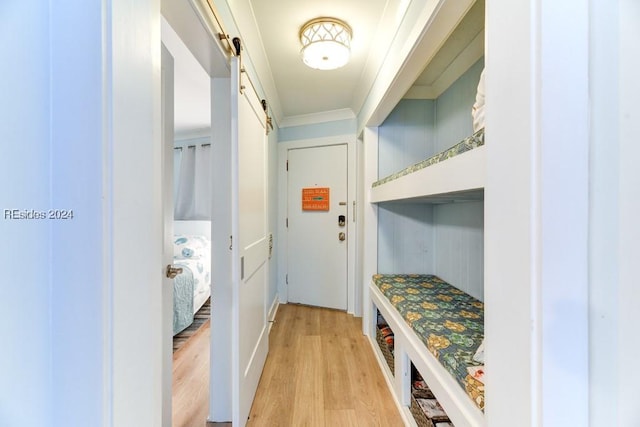 mudroom featuring ornamental molding, light hardwood / wood-style floors, and a barn door