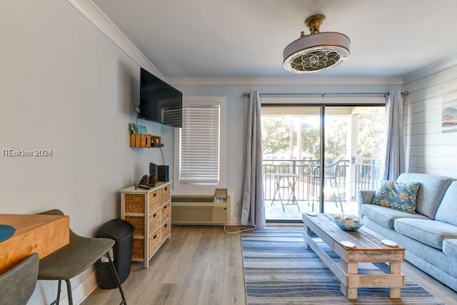 living room featuring ornamental molding, a wall mounted AC, and light hardwood / wood-style flooring