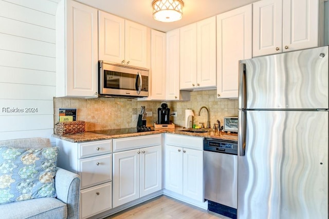 kitchen featuring white cabinetry, sink, stainless steel appliances, and dark stone counters