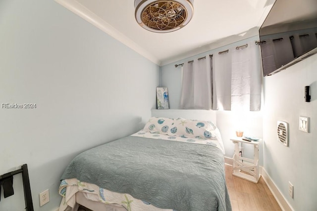 bedroom with crown molding and light hardwood / wood-style flooring