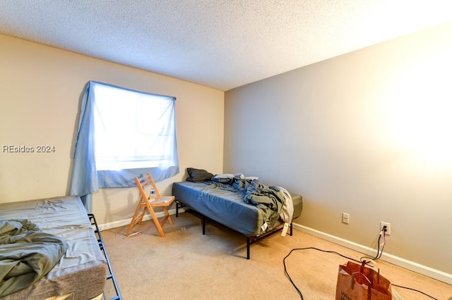 bedroom featuring light carpet and a textured ceiling