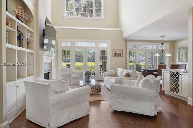 living room featuring french doors, a notable chandelier, dark hardwood / wood-style floors, and a high ceiling