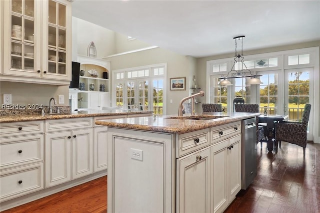 kitchen featuring pendant lighting, sink, a kitchen island with sink, light stone counters, and stainless steel dishwasher