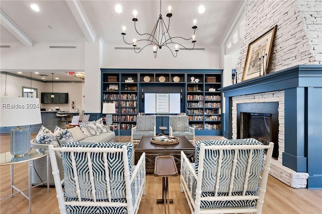 living room with built in shelves, a chandelier, light wood-type flooring, beamed ceiling, and a fireplace