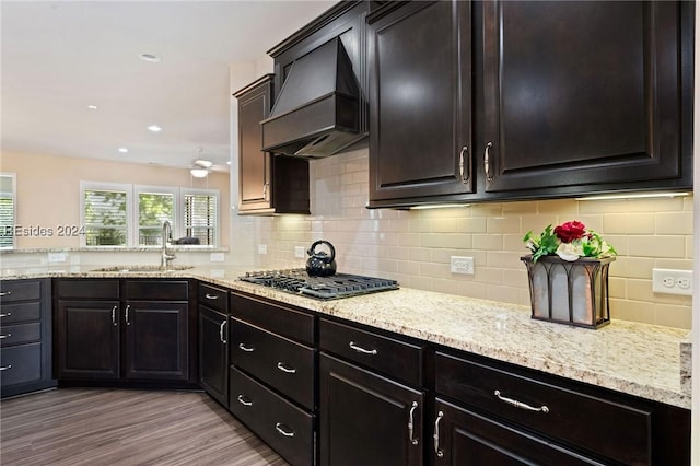 kitchen featuring sink, light hardwood / wood-style flooring, gas cooktop, custom range hood, and decorative backsplash