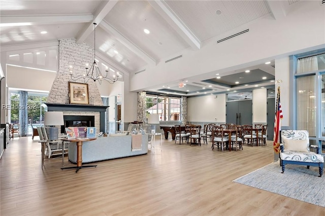 living room featuring beam ceiling, high vaulted ceiling, a fireplace, and light hardwood / wood-style flooring