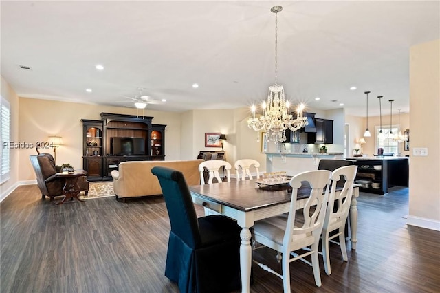 dining room with ceiling fan with notable chandelier and dark hardwood / wood-style flooring