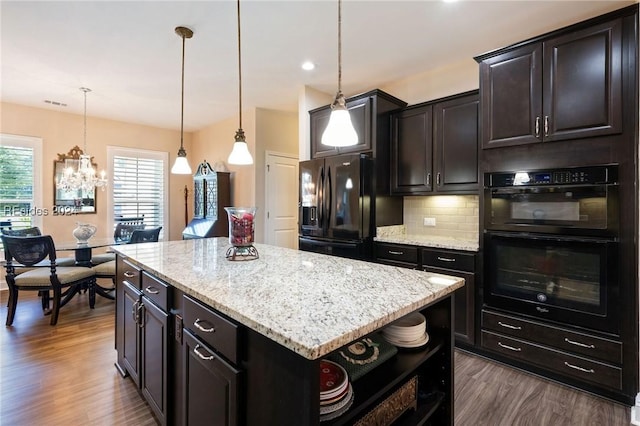 kitchen featuring wood-type flooring, decorative light fixtures, a center island, decorative backsplash, and black appliances