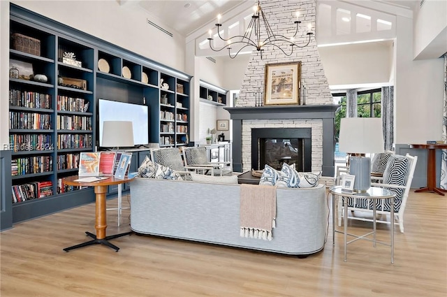 living room featuring built in features, a fireplace, wood-type flooring, a notable chandelier, and beam ceiling