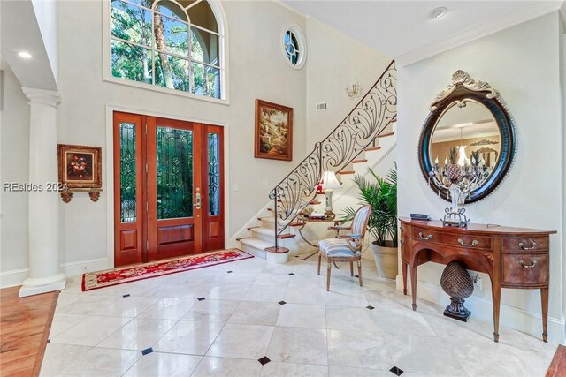 foyer with a towering ceiling, ornamental molding, and ornate columns