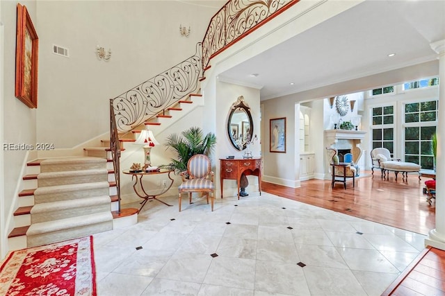 tiled foyer with crown molding, ornate columns, and a high ceiling