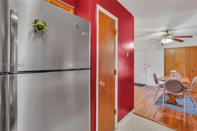 kitchen featuring ceiling fan, stainless steel fridge, light hardwood / wood-style floors, and a textured ceiling