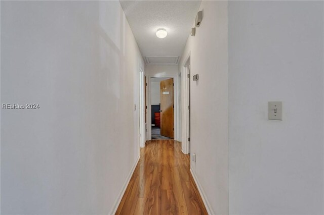 hall featuring a textured ceiling and light hardwood / wood-style floors