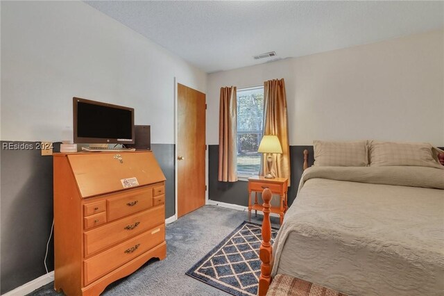 bedroom with a textured ceiling and dark colored carpet