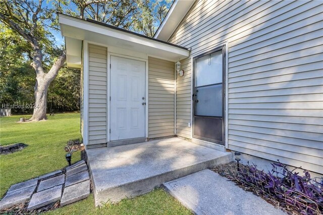 view of exterior entry with a yard