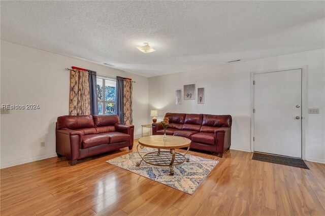 living room featuring light hardwood / wood-style flooring and a textured ceiling