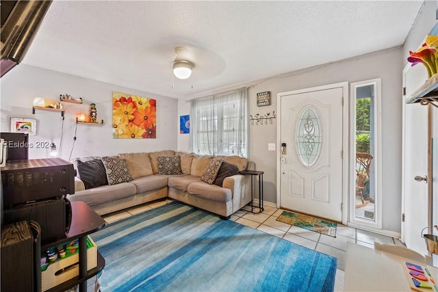 living room featuring light tile patterned floors, a textured ceiling, and ceiling fan