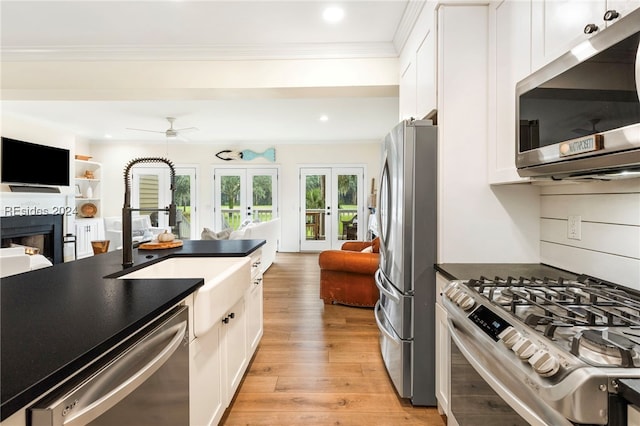 kitchen featuring crown molding, appliances with stainless steel finishes, white cabinetry, french doors, and light wood-type flooring